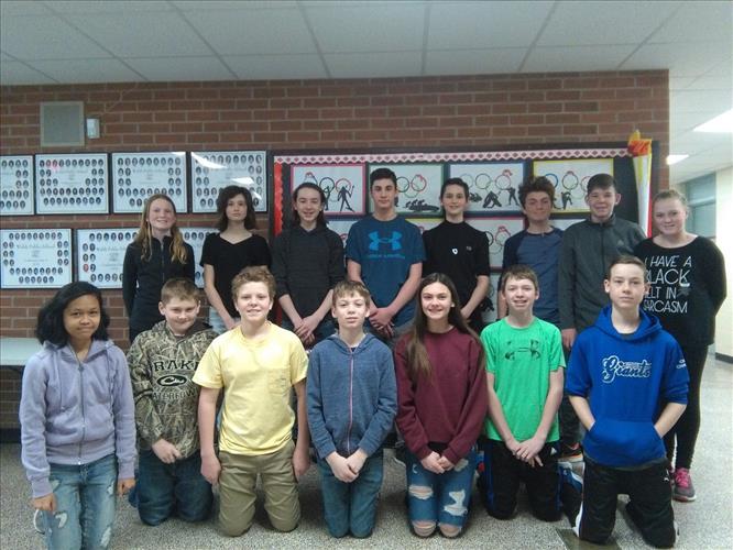 A group of students poses in two rows in a school hallway