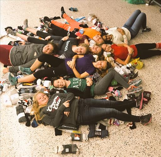 A group of students reclines in a hallway among hundreds of pairs of socks