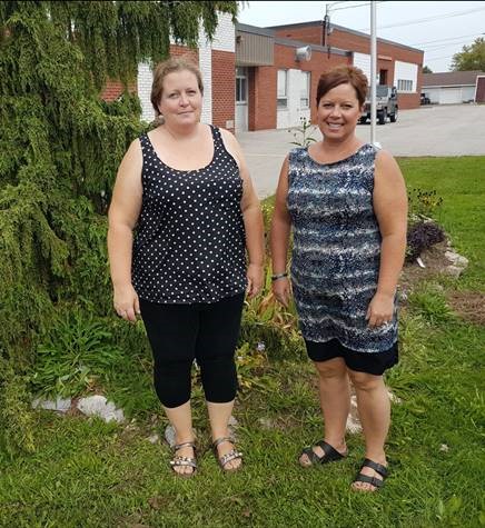 Two smiling Educational Assistants stand outside of school 